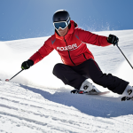 **A skier carving down a perfectly groomed slope on Rossignol Hero Elite ST Ti skis. Focus on the skis' edge contact with the snow and the skier's controlled, aggressive posture.** (Emphasizes carving skis on a prepared run)